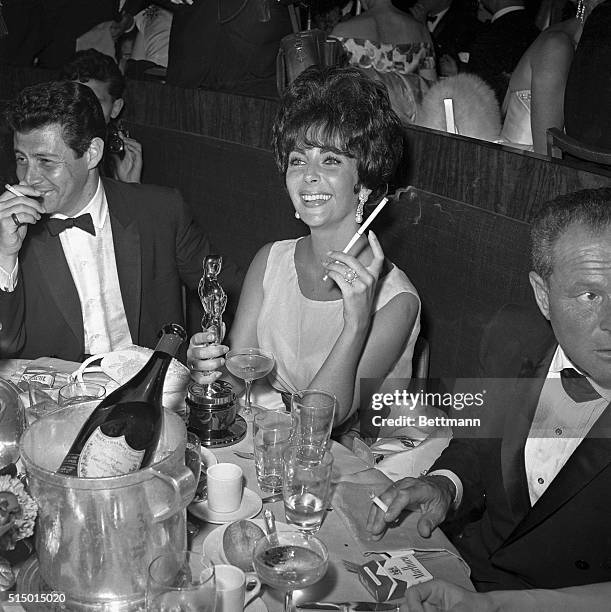 Hollywood, CA- Actress Elizabeth Taylor admires her first "Oscar" at a party following the Academy Award presentation. Miss Taylor won the award as...