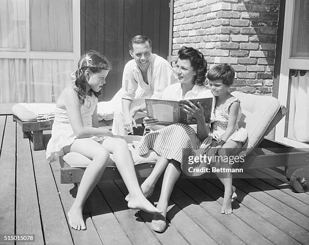 Rita Hayworth reads a book to her daughters Rebecca and Yasmin .