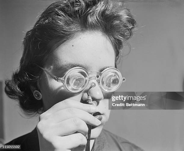 Miss Stephanie Diamond holds in her hand between tweezers, the world's smallest eye lens, which weighs 3/10,000ths of an ounce and is less than a...