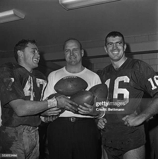 Washington Redskins coach Bill McPeak holds four footballs in the dressing room signifying the four touchdowns halfback Dick James made during the...