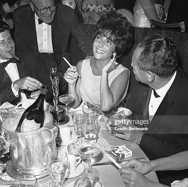 Actress Elizabeth Taylor, her Oscar before her, demonstrates her happiness as she relaxes at a champagne party following the Oscar ceremony 4/17....