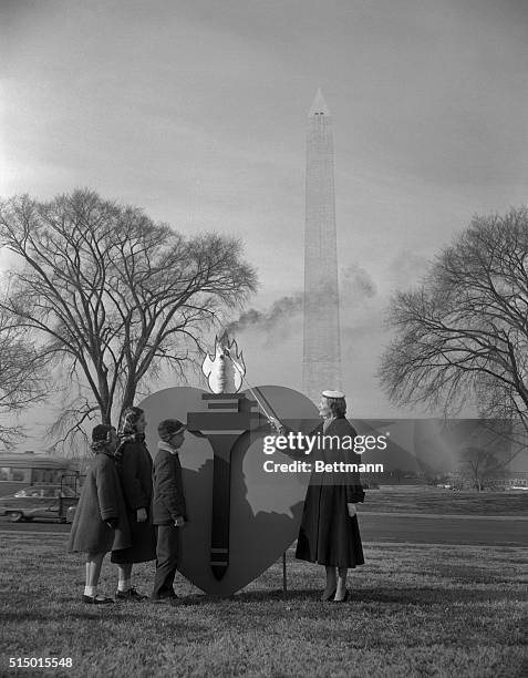 Mrs. Richard Nixon, wife of the Vice president, lights the torch of the Heart that is the emblem of the American Heart association, as children who...