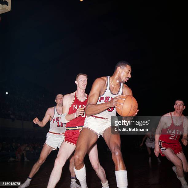 Philadelphia, PA: Close up of Wilt Chamberlain , as he comes down with rebound and looks for teammate. Behind him are John Kerr of the Syracuse...