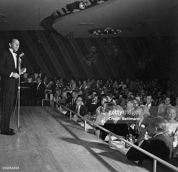 Frank Sinatra sings on the stage of the Sands Hotel. At the tables in the front are Jack Benny, several unidentified people, Kim Novak , Cole Porter,...