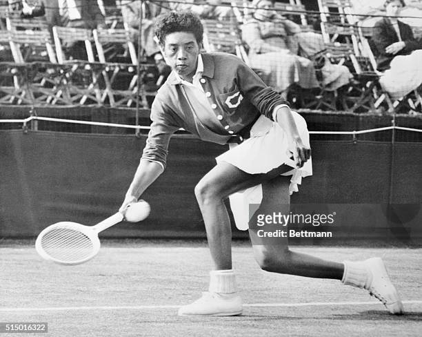 American tennis star Althea Gibson hits a return shot to Mlle. Monnot during her singles match at the Surrey Grass Court Championship, held at the...