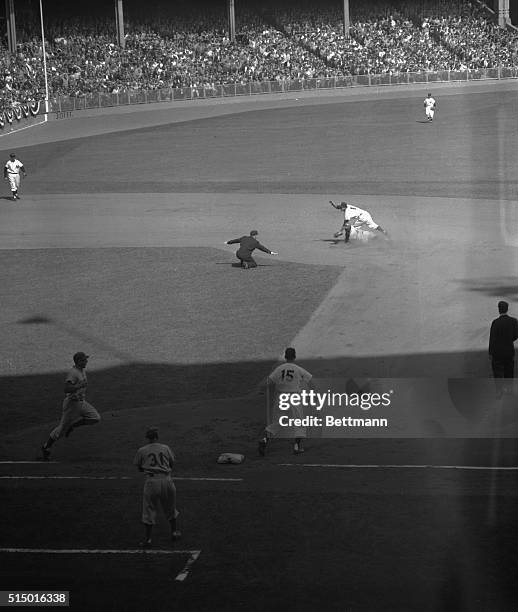 Jackie Robinson of the Dodgers is shown sliding safely into second as Billy Martin gets McDougald's throw too late, while Hodges, who singled races...