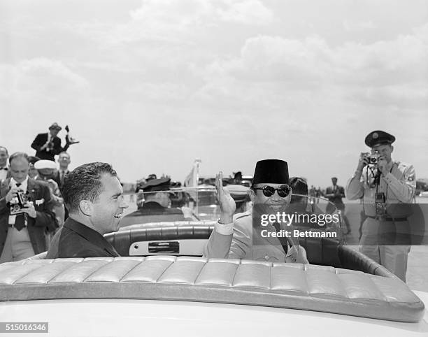 Asian leader responds to capital welcome. Washington, D.C.: President Sukarno of Indonesia waves from his open limousine in response to greeting...
