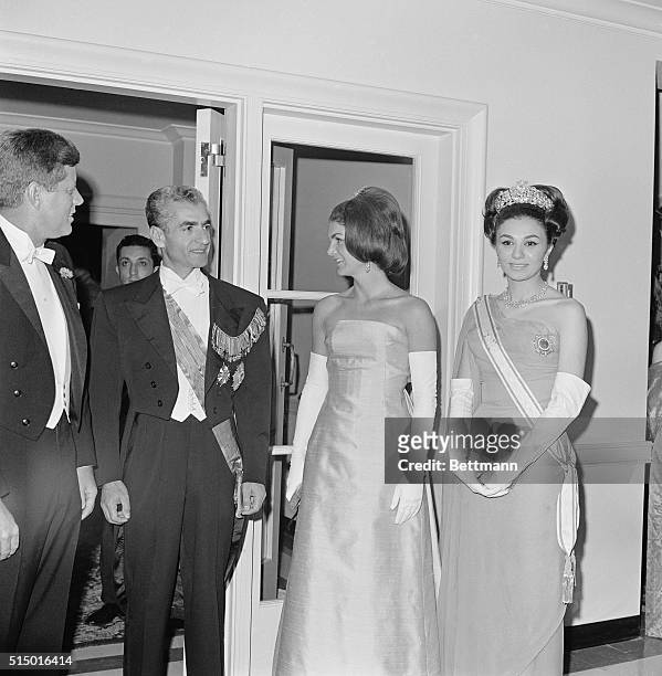 President and Mrs. Kennedy are escorted into the lobby of the Iranian Embassy as they arrive for a dinner in their honor given by the Shah Mohammed...