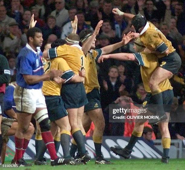 Australian players congratulate each other as French center Emile Ntamack looks dejected after the Rugby World Cup 1999 final game opposing France to...