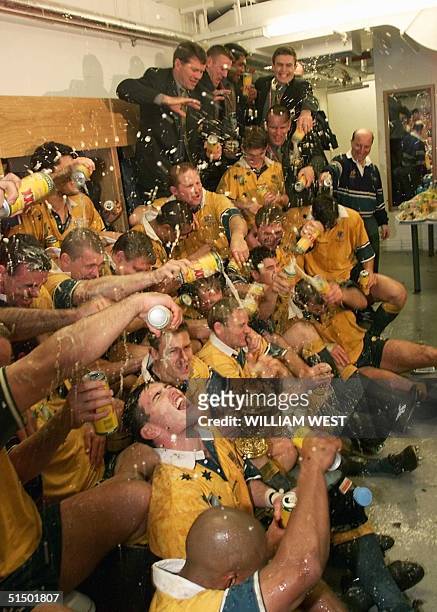 Australian center Daniel Herbert celebrates as his teammates pour beer all over him in the locker room after the Rugby World Cup 1999 final game...