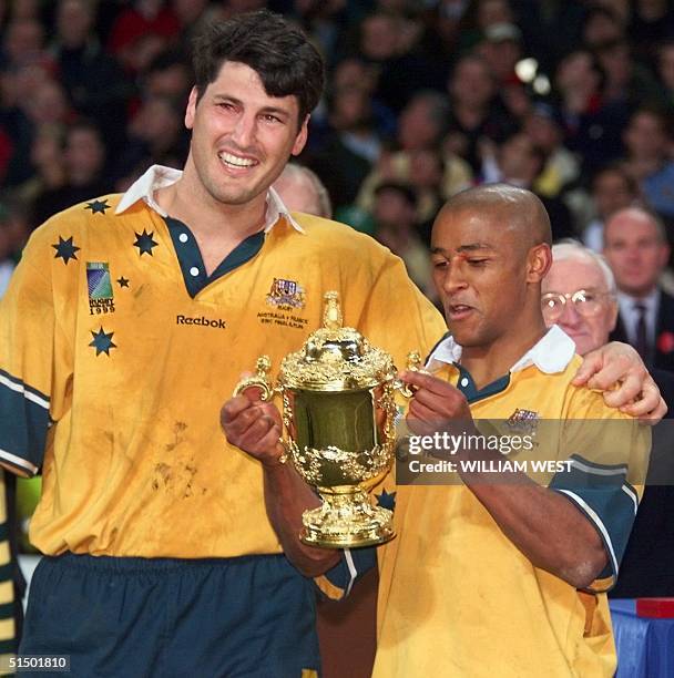 Australian lock and captain John Eales and Australian scrum-half George Gregan pose with the cup after the Rugby World Cup 1999 final game between...