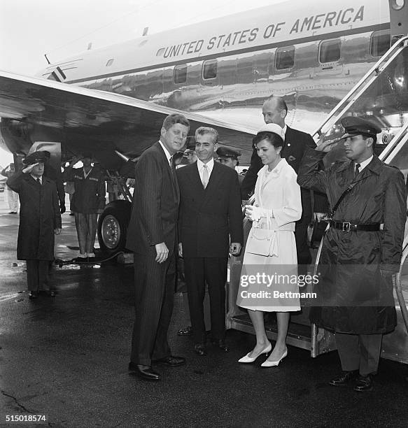 President Kennedy greets Shah Mohammad Reza Pahlavi of Iran and Empress Farah as they arrive for a three day state visit. Rain caused the welcoming...