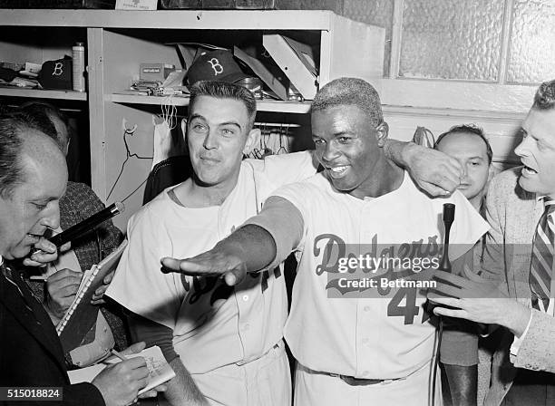 Jackie Robinson, who broke up the ten inning scoreless tie with a sharp hit into left field scoring Jim Gilliam, shows pitcher Clem Labine who hurled...