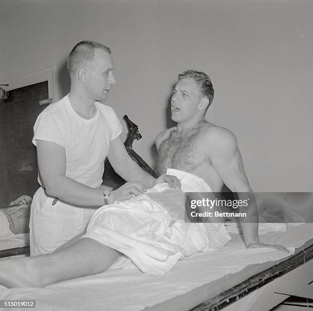 Chicago Black Hawks' left wing Bobby Hull is stretched out on the padded table in trainer Nick Garen's medicine room here 1/28, while Garen dutifully...