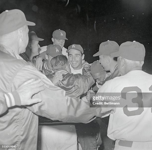 Dodgers' Sandy Koufax, wearing a big grin, is mobbed by jubilant teammates 6/30 after he pitched a no-hit, no run game giving the Dodgers a 5-0...