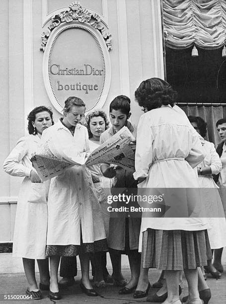 Group of midinettes working in the Christian Dior House of Fashion in Paris crowd around a newspaper to read the shocking news of Dior's death in...