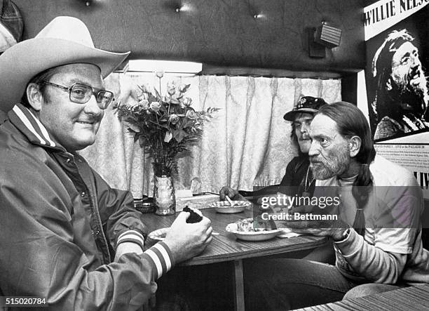 Gov. James R. Thompson enjoys a bowl of Texas jailhouse chili and jalapino pepper cornbread with country music star Willie Nelson between Nelson's...
