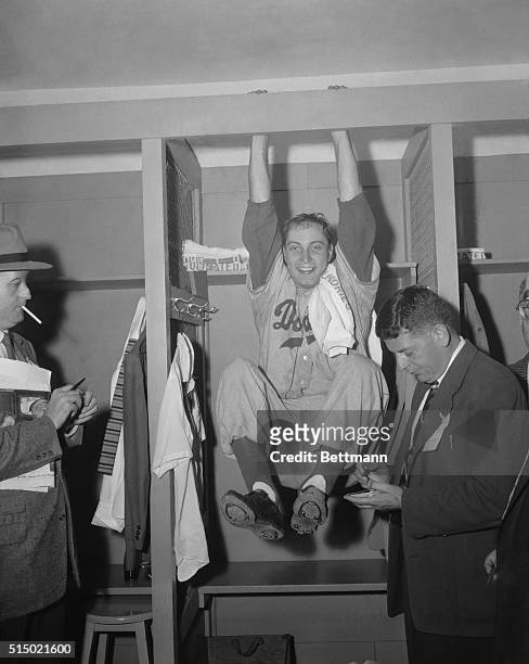 Swinging from the Rafter. New York, New York: Beside himself with joy, Johnny Podres swings from the rafter in the dressing room after hurling the...
