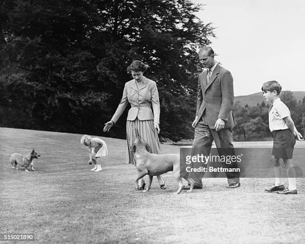 Royal Family at Balmoral. Princess Anne tempts the queen's corgi, Sugar, with a ball, and the Duke of Edinburgh's dog, Candy, looks up at Queen...