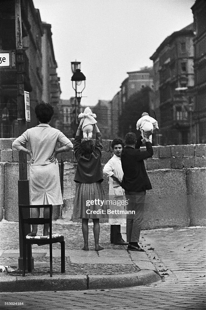 Father and Mother Showing Baby Above Wall