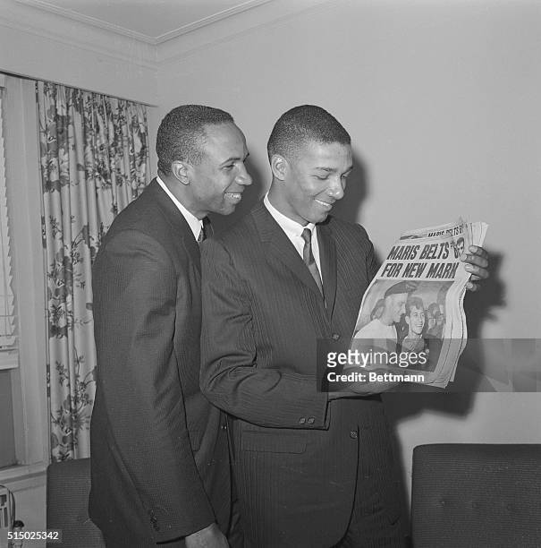 Cincinnati Reds slugger Frank Robinson and his roommate Vada Pinson look at front page of newspaper which pictures Roger Maris and headlines his...