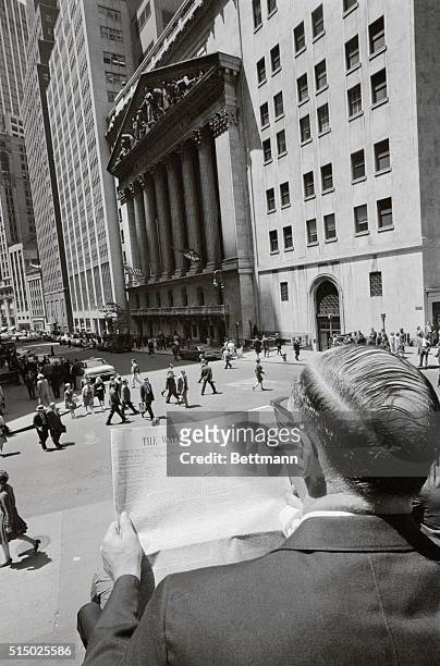 Seated on the steps of Subtreasury Building in Lower Manhattan, an office worker reads Wall Street Journal May 29th across the street from the New...