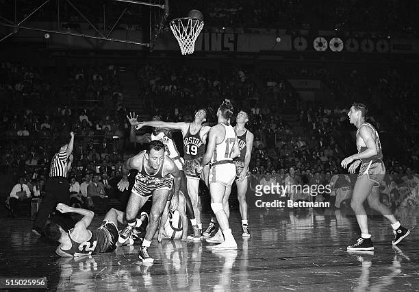 Teetering on the rim of the basket, layup of Ray Felix of the Knicks, holds teammates and Boston Celtics in suspense. Big Arne Risen of the Celts...