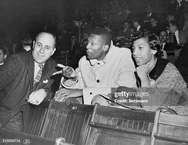 Boston Celtics manager Red Auerbach is shown talking with Olympic star Bill Russell as Russell's wife, Rose, looks on at Madison Square Garden....