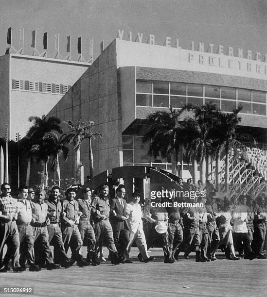 Cuban Prime Minister Fidel Castro, center, walks arm-in-arm with President Osvaldo Dorticos and his brother, Major Raul Castro during parade...