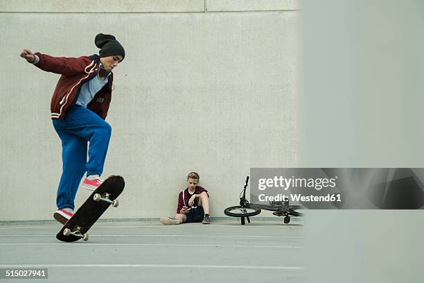 two boys with bmx bike and skateboard on parking level - skateboard leaning against wall stock pictures, royalty-free photos & images