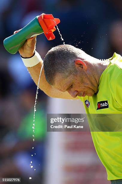 Umpire Justin Schmitt pours water over his head to cool down at the three quarter time break during the NAB Challenge match between the Fremantle...