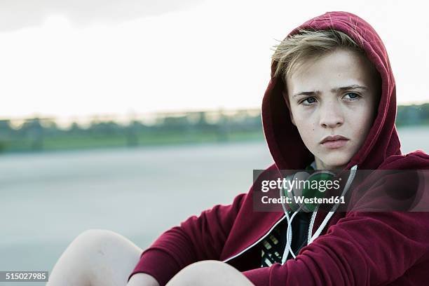 serious teenage boy outdoors wearing hooded jacket - blonde boys stockfoto's en -beelden