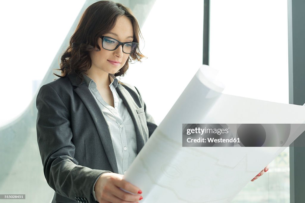 Businesswoman in office looking at blueprint