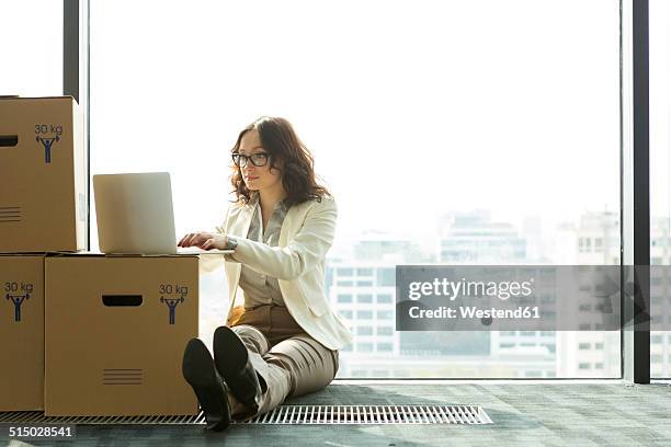 businesswoman using laptop on empty office floor with cardboard boxes - starting a new business stock pictures, royalty-free photos & images