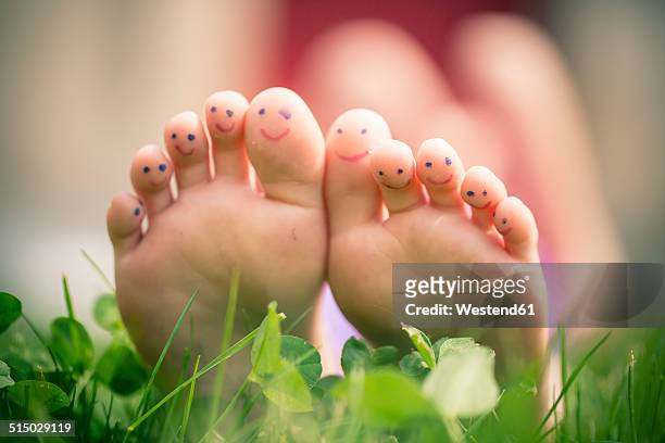 little girl's feet with painted toes lying in grass - lustige füße stock-fotos und bilder