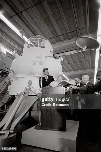 President John F. Kennedy is set off by an exhibit of one of the National Aeronautics and Space Agencies proposed lunar landing vehicles, or "Moon...