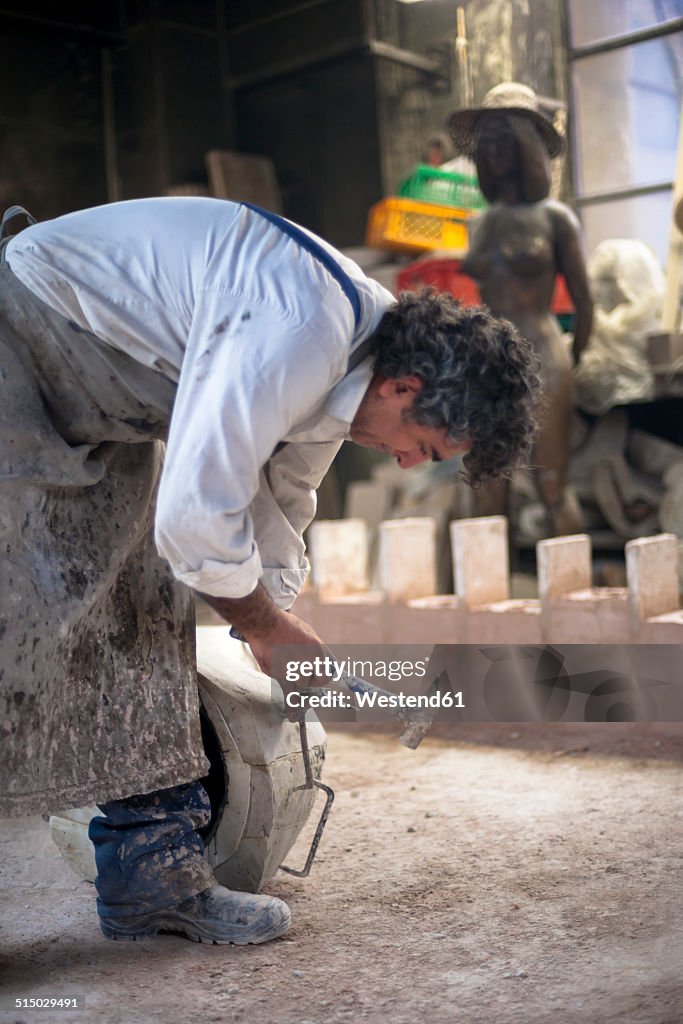 Germany, Munich, Art foundry worker working on casting mould