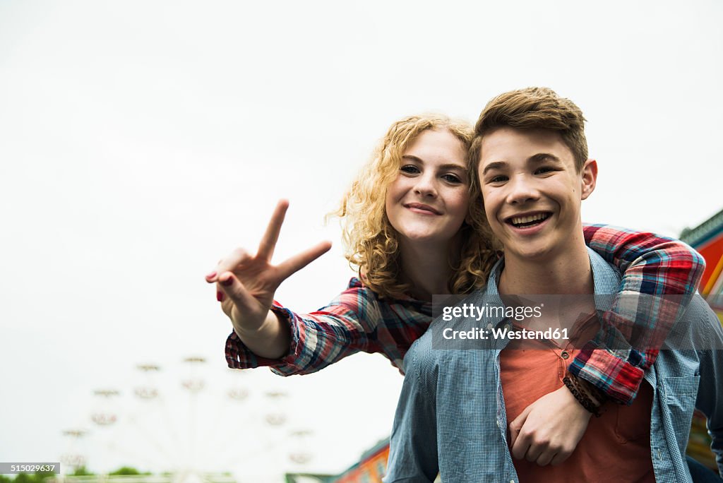 Portrait of happy teenage couple showing victory-sign