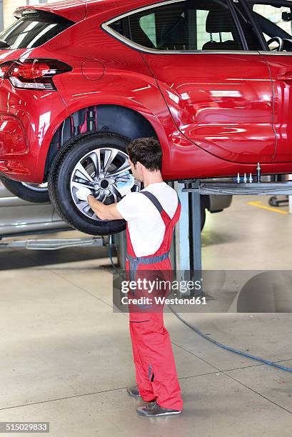 car mechanic in a workshop changing tire - issare foto e immagini stock