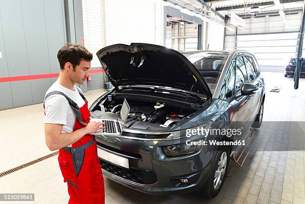 car mechanic in a workshop using modern diagnostic equipment - mechatronics stock-fotos und bilder