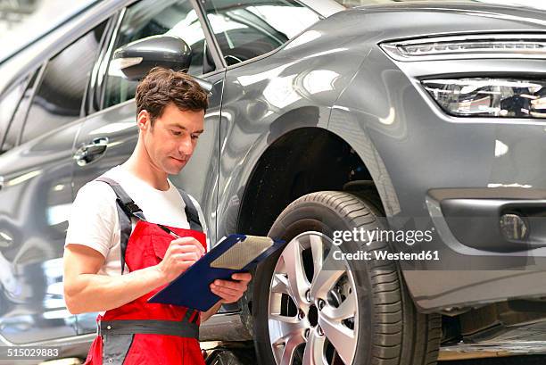 car mechanic in a workshop holding clipboard - car inspection stock pictures, royalty-free photos & images