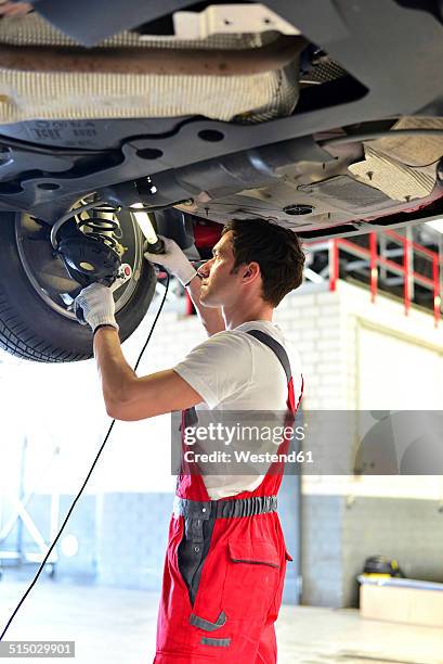 car mechanic in a workshop working at car - issare foto e immagini stock