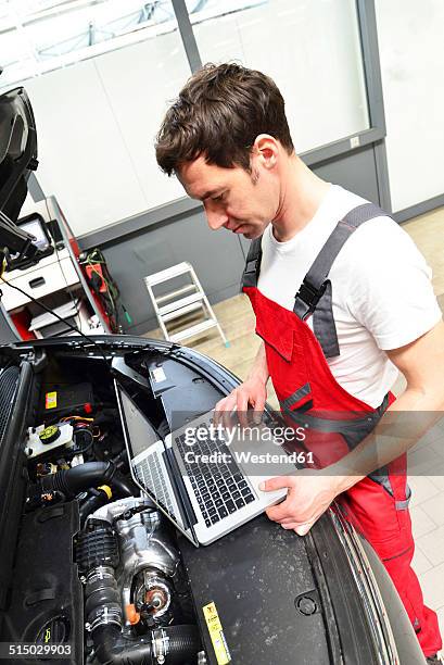 car mechanic in a workshop using modern diagnostic equipment - mechatronics stock-fotos und bilder