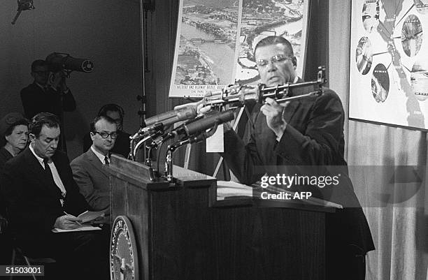 Secretary of Defense Robert McNamara displays 26 April 1965 during a press conference in Washington, DC, a Chinese-made machine-gun seized in South...
