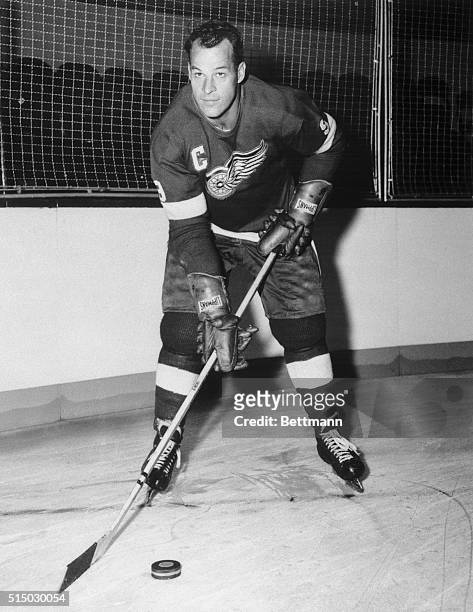 Gordon Howe, of the Detroit Redwings, poses with a puck on the ice. Full-length photograph.