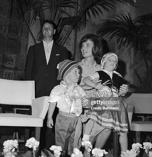 Caroline Kennedy, wearing the colorful costume of a little Italian tarantella dancer, sits upon her mother's knee, as she and Mrs. Kennedy attend a...