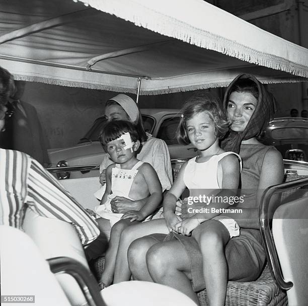 Caroline Kennedy smiles charmingly while sitting on her mother's lap during a ride to the sea shore in their fringe-canopied buggy August, 12th. Mrs....