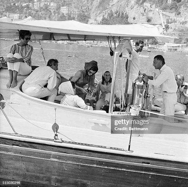 Mrs. Jacqueline Kennedy checks over a camera before leaving on a day-long cruise aboard a yacht owned by the Gnelli family of Turin, owners of the...