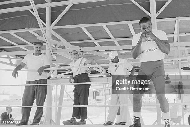 Aurora, Illinois: Heavyweight challenger Sonny Liston does a little shadow boxing as his trainer Willie Reddish keeps a close look at the stop watch....