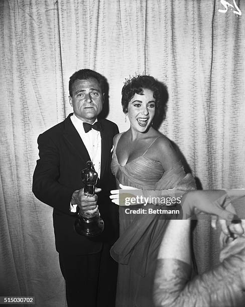 Hollywood, CA- 29th Annual Academy Awards presenations at the Pantages Theater. Mike Todd kisses Actress Elizabeth Taylor while holding an Oscar.